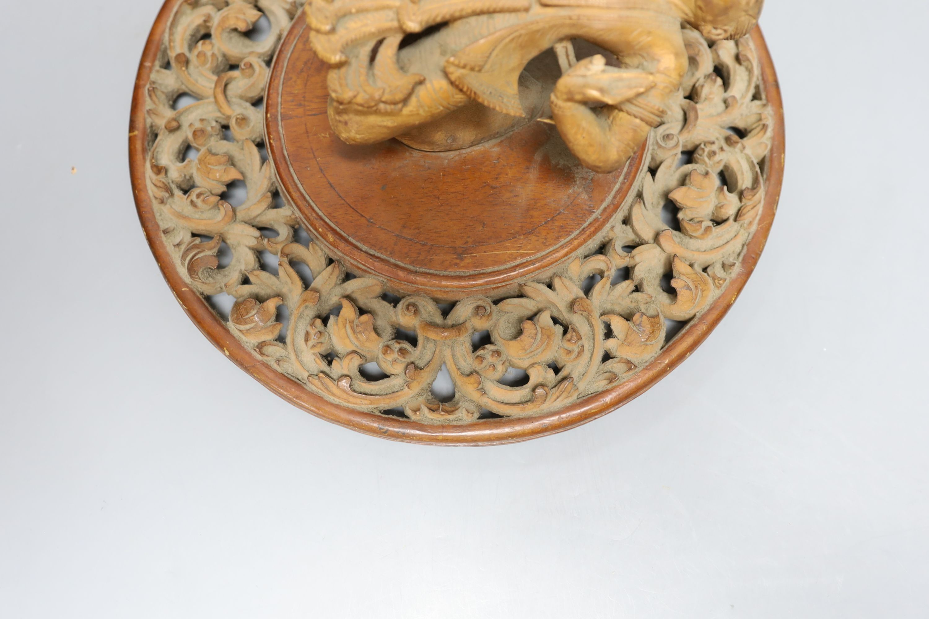 A Chinese blue and white plate with floral decoration, 23cm diameter, together with another plate and wooden panel relief of oriental figure (3)